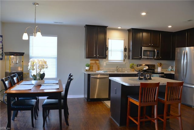 kitchen with sink, dark hardwood / wood-style flooring, hanging light fixtures, a center island, and stainless steel appliances