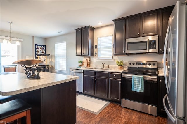 kitchen featuring dark brown cabinetry, sink, hanging light fixtures, appliances with stainless steel finishes, and dark hardwood / wood-style flooring