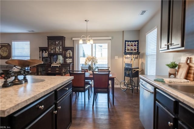 kitchen with hanging light fixtures, plenty of natural light, dark wood-type flooring, and stainless steel dishwasher