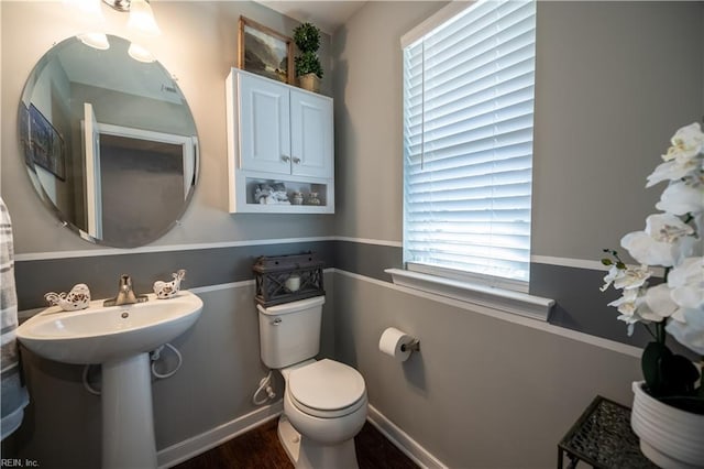 bathroom featuring wood-type flooring, toilet, and a healthy amount of sunlight