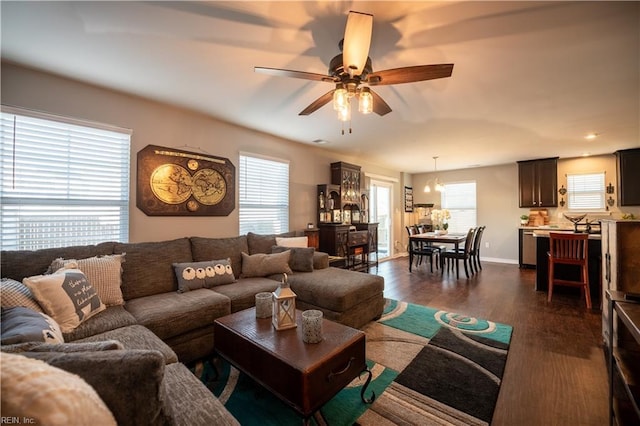 living room with dark wood-type flooring, ceiling fan, and a wealth of natural light