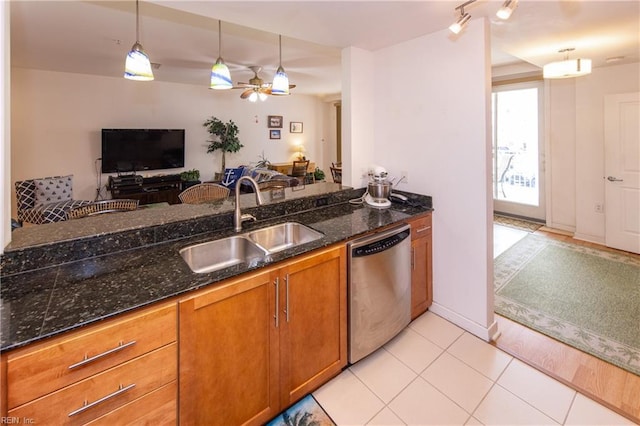 kitchen with light tile patterned flooring, sink, hanging light fixtures, dishwasher, and dark stone counters