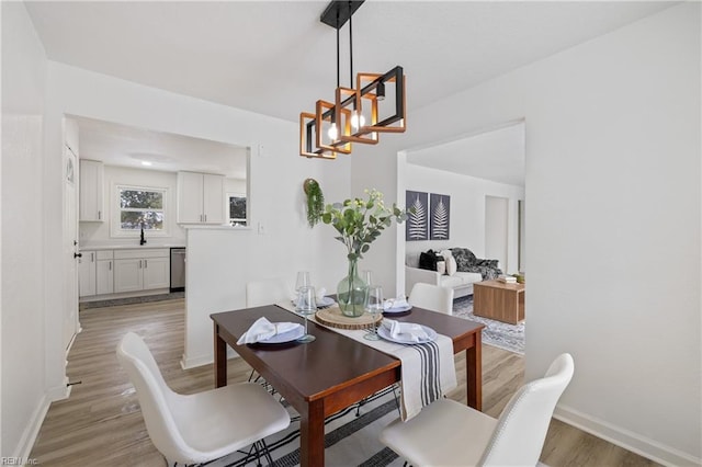 dining room featuring sink, a chandelier, and light hardwood / wood-style floors