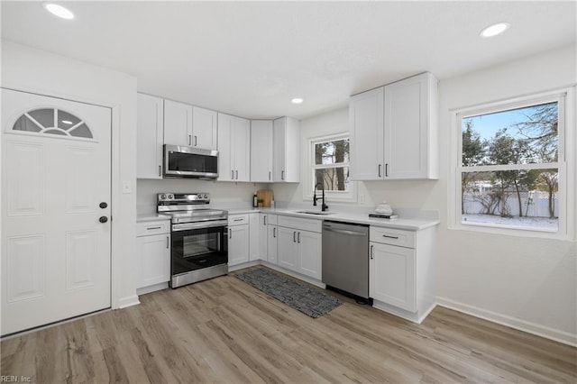 kitchen featuring sink, light hardwood / wood-style floors, white cabinets, and appliances with stainless steel finishes