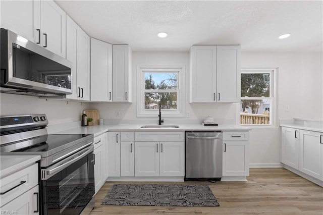 kitchen with white cabinetry, appliances with stainless steel finishes, sink, and light hardwood / wood-style flooring