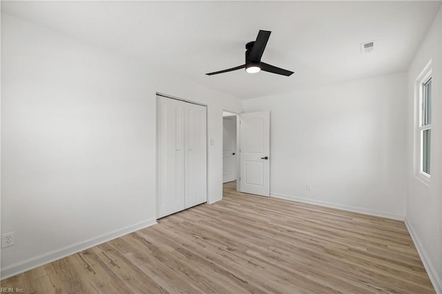 unfurnished bedroom featuring ceiling fan, light wood-type flooring, and a closet