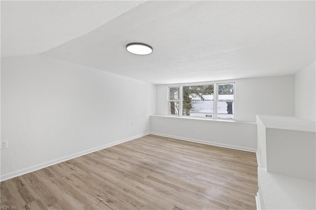 unfurnished room with a textured ceiling and light wood-type flooring