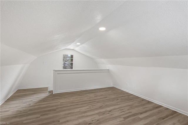 bonus room with dark hardwood / wood-style flooring, vaulted ceiling, and a textured ceiling