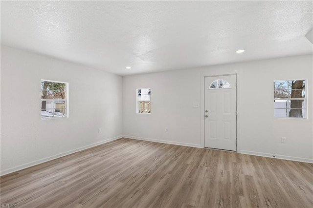 foyer featuring a wealth of natural light, a textured ceiling, and light wood-type flooring