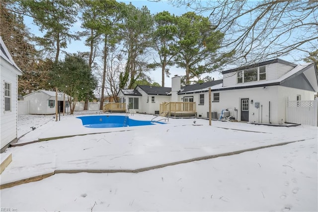 snow covered pool with central AC, a deck, and a shed