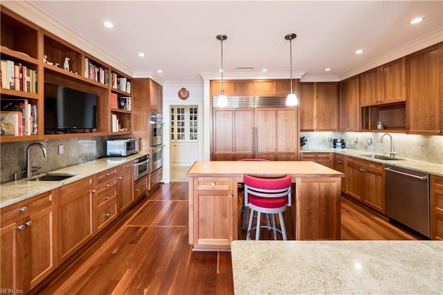 kitchen with sink, hanging light fixtures, stainless steel appliances, and a center island