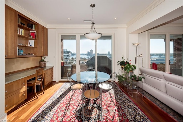 interior space featuring hardwood / wood-style flooring, crown molding, and built in desk