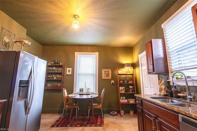 kitchen with stainless steel appliances, sink, and dark stone counters