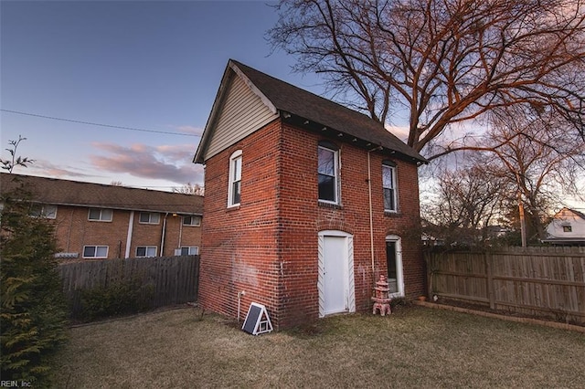 property exterior at dusk with a lawn