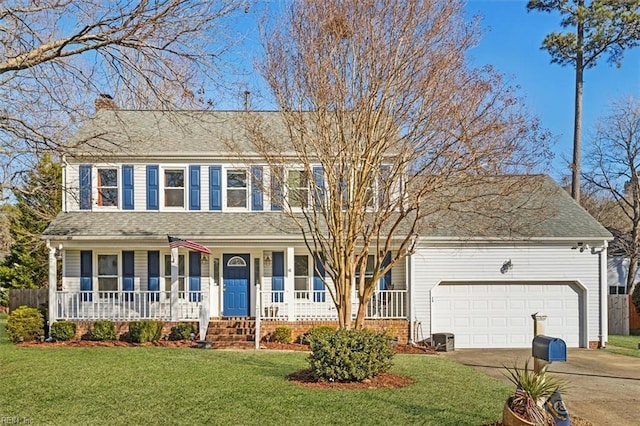 colonial house featuring a porch, a garage, and a front lawn