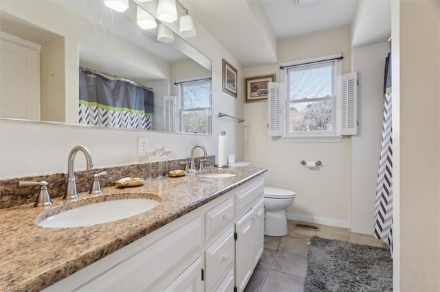 bathroom featuring tile patterned flooring, vanity, toilet, and a healthy amount of sunlight