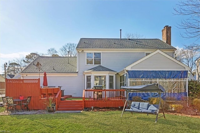 rear view of property featuring a wooden deck and a lawn