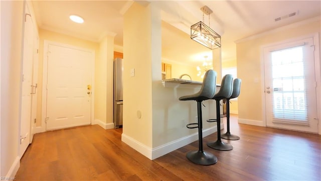 hallway featuring crown molding, dark wood-type flooring, and an inviting chandelier