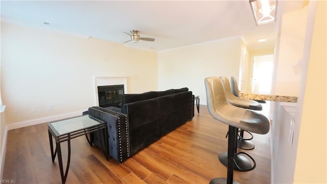 living room with hardwood / wood-style flooring, crown molding, and ceiling fan