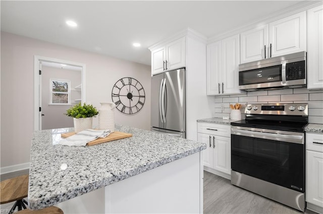 kitchen with a kitchen island, white cabinetry, backsplash, stainless steel appliances, and light wood-type flooring