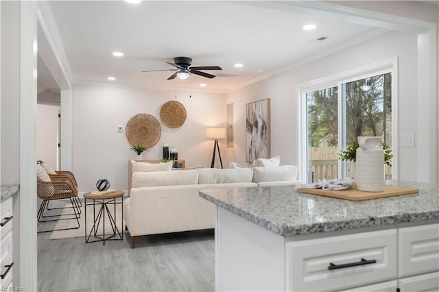 living room with crown molding, ceiling fan, and light wood-type flooring