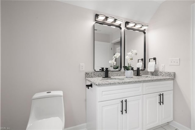 bathroom with lofted ceiling, vanity, toilet, and tile patterned floors