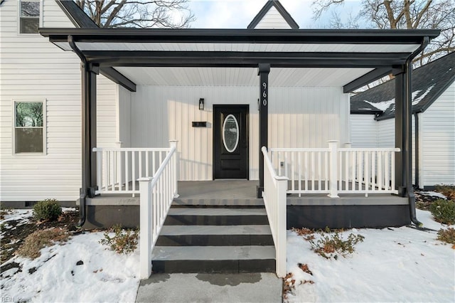 snow covered property entrance with a porch