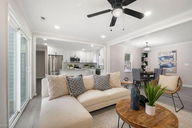 living room featuring crown molding, ceiling fan, and light wood-type flooring