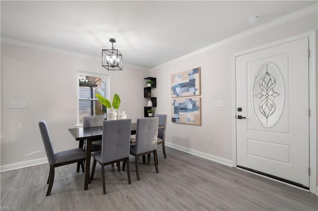 dining area with a notable chandelier, light hardwood / wood-style flooring, and ornamental molding