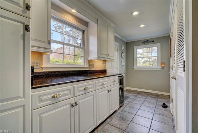 kitchen featuring white cabinetry, dark stone counters, tasteful backsplash, and plenty of natural light