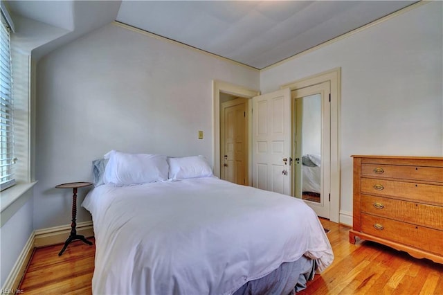 bedroom with vaulted ceiling and light wood-type flooring