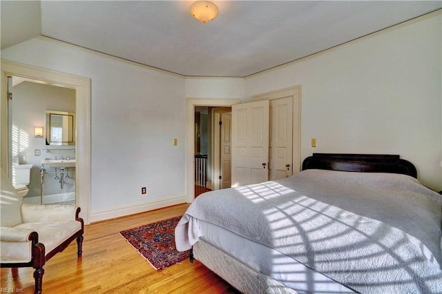 bedroom with hardwood / wood-style flooring and ensuite bathroom