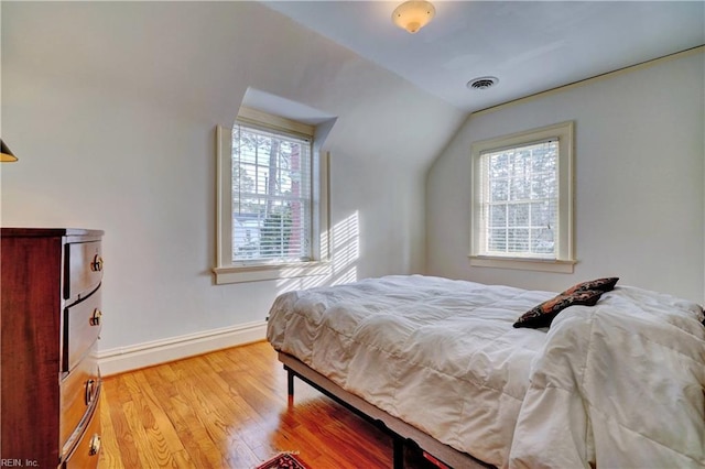 bedroom with multiple windows, hardwood / wood-style floors, and lofted ceiling