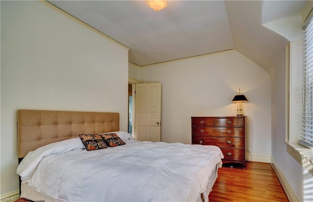 bedroom with wood-type flooring, vaulted ceiling, and multiple windows