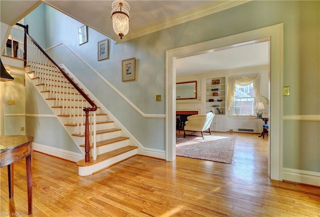 stairs with hardwood / wood-style flooring, ornamental molding, and built in features