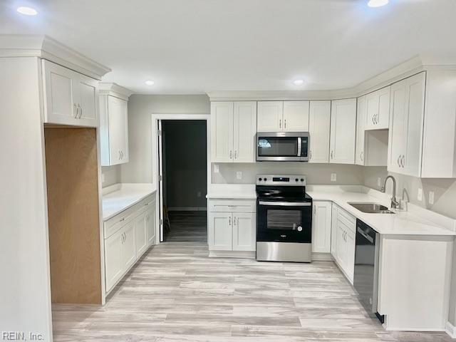 kitchen with white cabinetry, appliances with stainless steel finishes, light hardwood / wood-style floors, and sink