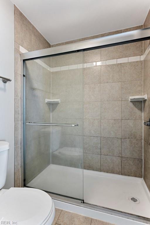 bathroom with walk in shower, toilet, and tile patterned flooring