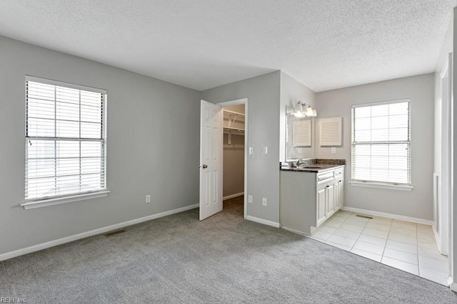 kitchen with light carpet, sink, white cabinetry, and a textured ceiling