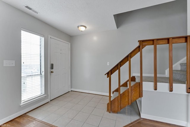 tiled entrance foyer featuring a healthy amount of sunlight and a textured ceiling