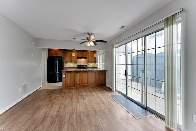 kitchen featuring ceiling fan, black refrigerator, backsplash, kitchen peninsula, and light wood-type flooring