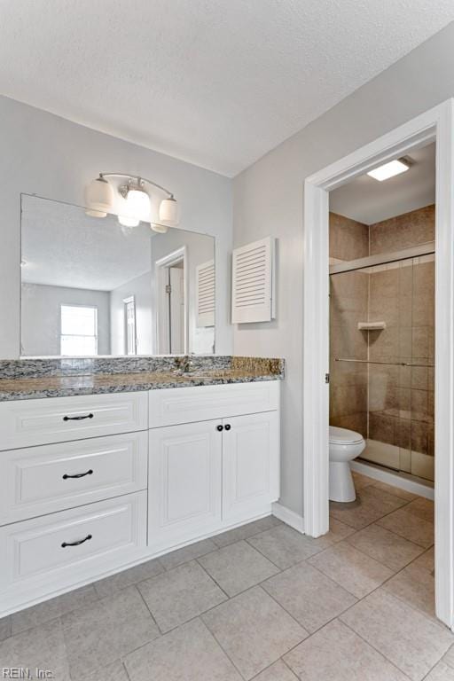 bathroom featuring vanity, walk in shower, toilet, tile patterned floors, and a textured ceiling