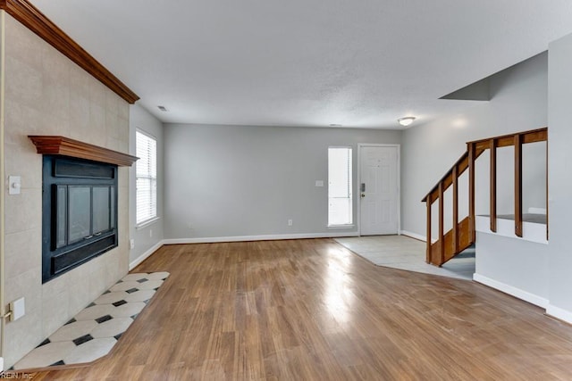 unfurnished living room featuring a tile fireplace and light wood-type flooring