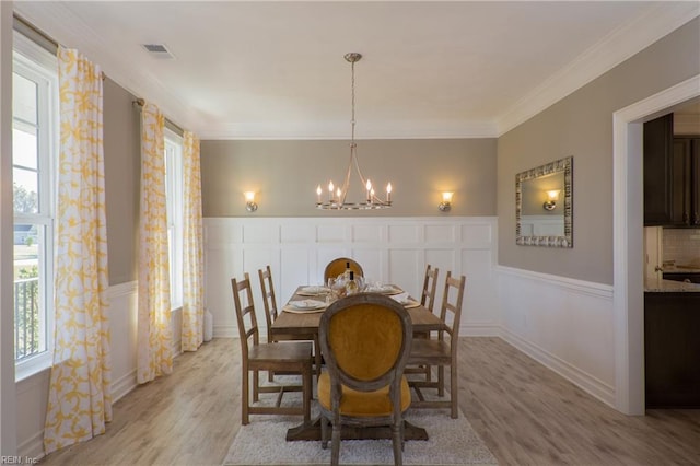 dining room with an inviting chandelier, light hardwood / wood-style flooring, and ornamental molding