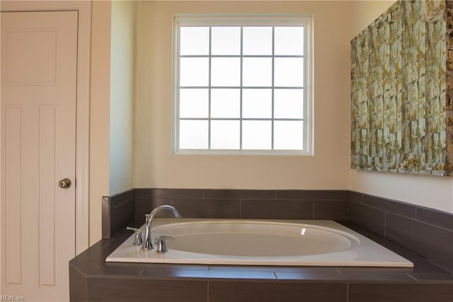 bathroom with tiled tub and a wealth of natural light