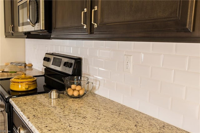 kitchen featuring stainless steel appliances, tasteful backsplash, dark brown cabinets, and light stone counters