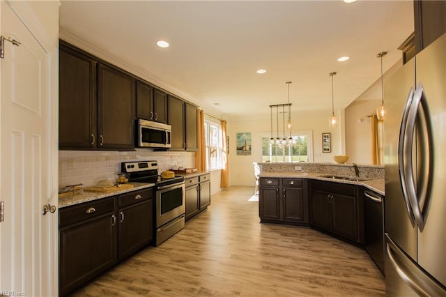 kitchen with pendant lighting, light stone counters, stainless steel appliances, and dark brown cabinetry