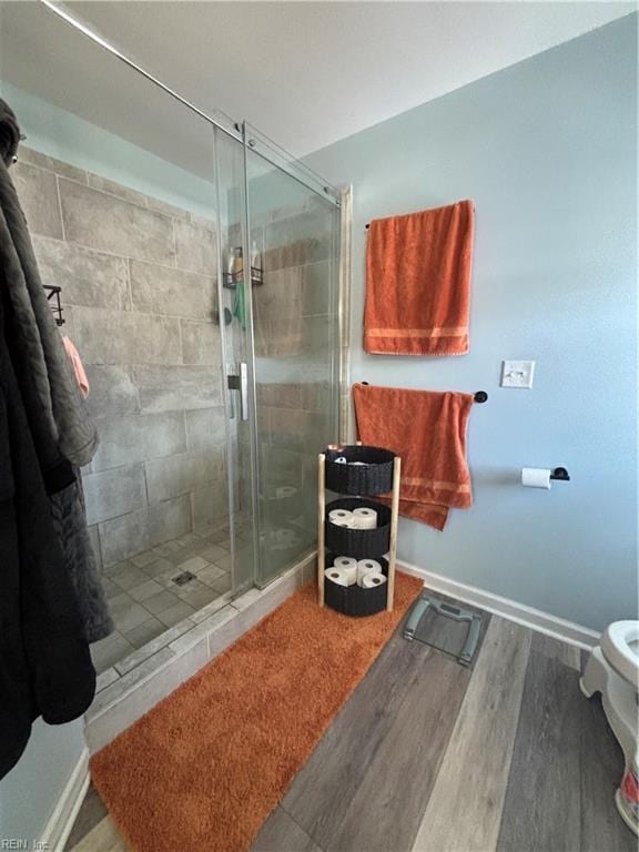 bathroom featuring wood-type flooring, toilet, and a shower with door