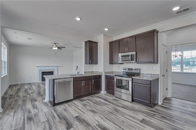 kitchen featuring sink, light hardwood / wood-style floors, kitchen peninsula, stainless steel appliances, and dark brown cabinets