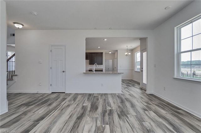 unfurnished living room featuring sink, dark wood-type flooring, and a chandelier