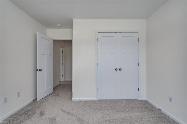 unfurnished bedroom featuring light colored carpet and a closet